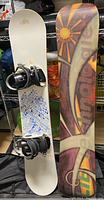 White snowboard showing top side with black bindings and blue graphic text.