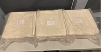 Three sealed packages of folded solid cream color table covers, each package labeled as Super Soft II, 52" x 114" sewn size.