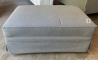 Blue and white plaid upholstered storage ottoman shown from a top angle.