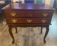 Front view of the cherry finish wooden cabriole leg table showing two drawers with brass handles and carved detailing.