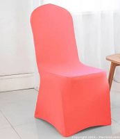 Single coral color spandex chair cover displayed on a chair to show fit and color.