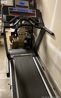 Full view of black and gray Epic treadmill in storage showing the belt, handles, and base.