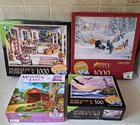 Photo showing all four puzzle boxes: two 1000-piece Wrebbit Perfalock puzzles, one 500-piece Wrebbit Perfalock puzzle, and one 300-piece Memory Lane puzzle.