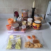 Wide view showing assortment of candles and candle holders on kitchen counter.