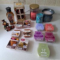 Photo of all candle lot items arranged on counter, showing wax melts, candles, oil, figurines, and wax warmer