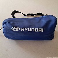 Photo of the Hyundai branded inflatable lounger inside its blue carrying bag with black strap.