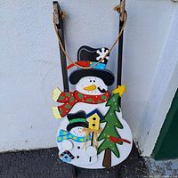 Wooden snowman decoration featuring two snowmen, Christmas tree with star, birdhouse, and rope hanger.