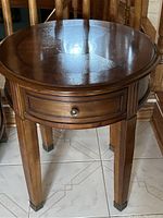 Front view of round side table showing overall design, drawer front, and leg style