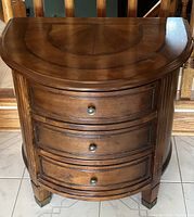 Front view of the semi-circular 3 drawer side table showing wood grain and metal knobs.