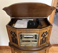 Full view of vintage Emerson stereo system with wooden cabinet, lid open revealing turntable and original manual on top