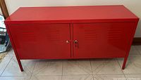 Full view of the IKEA red metal locker style cabinet showing two doors and the vented design on doors.