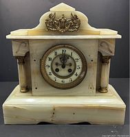 Front view of large white onyx mantel clock with decorative gold accents and rounded columns on sides.