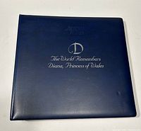Blue leather-bound album cover with silver foil title 'The World Remembers Diana, Princess of Wales'.
