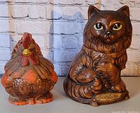 Photo of two cookie jars, brown cat labeled 'Cookies' and detailed rooster with orange and red coloring.