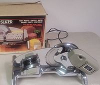 Profile view of Rival electric food slicer on display table with original box in background.