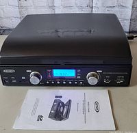 Front view of Jensen digital encoding music system with user manual showing control panel including volume, tuning knobs, buttons, USB port, and digital display.