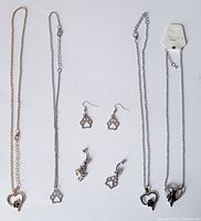 Overview of pet-themed necklaces and earrings made of silver-tone metal with paw and heart designs