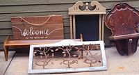 Photo of four varied decorative wall hangings arranged side by side on the ground against a wall