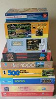 Stack of ten new sealed puzzle boxes showing a variety of themes and piece counts