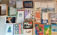 Collection of assorted blank and written note and Christmas cards arranged for display, showing various packaged and loose cards in different designs and colors.