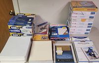 Lot overview showing boxes of white envelopes, reams of white paper, photo paper, and labels.