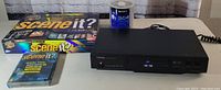 Wide shot of Toshiba DVD player with Scene It? DVDs and Sony DVD-R blank discs on top and beside the player.