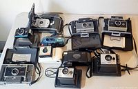 Overview of ten Polaroid cameras on table