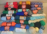 Overview of yarn skeins in multiple colors and brands laid out for display