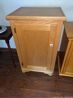 Front view of wooden cabinet with closed door, white knob, and metal hinges.