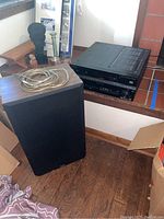 Pioneer VSX-1016TXV receiver and Jensen speaker with wire, placed on floor and wooden ledge.