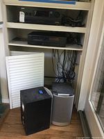 Three shelf unit with Sony STR-DH700 receiver on top shelf, Kenwood DPM3360 CD player on middle shelf, and two JBL Venue series speakers on floor, one black and one silver-gray, with various wires visible.