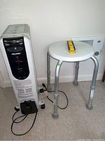 Pelonis heater and adjustable stool side by side on floor near wall