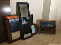 All four mirrors and the framed landscape art arranged together on floor, showing size differences and frame styles