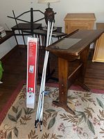 View of all items including black metal folding music stand, boxed light-duty easel, and wooden desk stand with angled top.