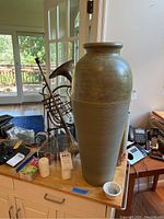 Front view of mantle or table with tall vase in foreground, trumpet and trombone behind, candles and matches visible