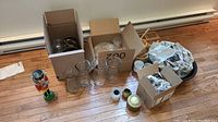 Group of glass vases, glass servingware, mugs, candle holders and nutcracker in cardboard boxes on floor