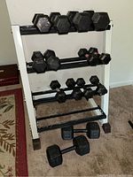 Front view of white A-frame rack loaded with multiple black cast iron hex dumbbells