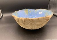 Side angle of the handmade decorative bowl showing the textured natural exterior and blue glazed interior.