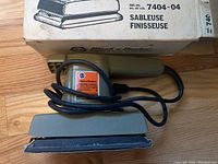 Photo showing the Black & Decker finishing sander alongside its original box with product label and model number 7404-04.
