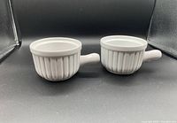 Two white ceramic French soup bowls with handles shown side by side on a black background.