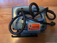 Top-side view of the Black & Decker B-151 utility jigsaw with coiled power cord on wooden surface.