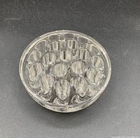 Top-down view of a clear round glass flower frog with 19 holes.