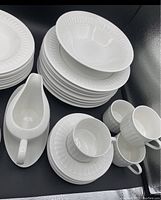 White porcelain Oneida Majesticware diningware arranged in stacks showing plates, bowls, cups, gravy boat, and salt & pepper shakers