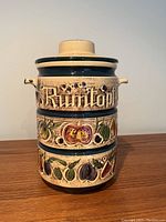 Side view of Rumtopf canister showing embossed fruit decoration and word 'Rumtopf'.