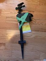 Full view of the sprinkler head mounted on a ground spike, taped with instruction manual underneath.