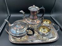 Photo of the entire tea set including the tray, teapot, covered pot, sugar bowl, and cream pitcher showing tarnish and designed handles.
