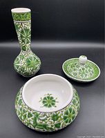 All three pieces arranged with black background, showing intricate green and white floral patterns, vase, candy bowl, and lid.