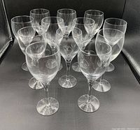 Twelve clear white wine glasses arranged in a group on a black background.