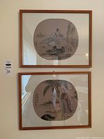 Framed wall with two Asian themed prints with wooden frames, showing their total view.