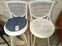 Pair of white wicker swivel bar stools side by side, one with a blue woven seat cushion.